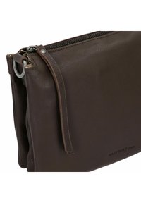 Clutch in pelle marrone con superficie texture, chiusura con zip e un accento anello color argento sul lato. Presenta un design semplice.