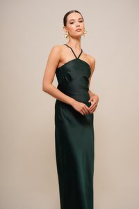 Rochie lunga din satin verde închis, cu decolteu halter și siluetă ajustată. Prezentând o textură netedă și drapaj elegant. Cercei statement din aur remarcabili.