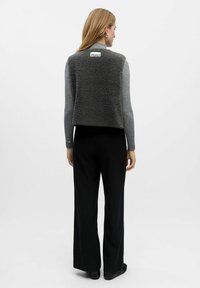 Grå fleece vest med en cropped design, der har en glat grå langærmet top under og sorte stribede bukser. Ryggen viser "OBJECT" label.