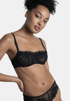 Soutien-gorge en dentelle noire avec des motifs floraux, en maille semi-transparente, avec des bretelles réglables et un design à encolure courbée.