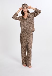 Conjunto de pijama de estampado de leopardo hecho de tela suave, que incluye una camisa de botones de manga larga y pantalones a juego, junto con una máscara para dormir.