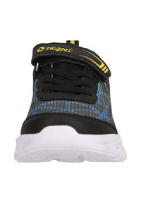 Svart idrottssko med ovandel i nät och blåa och gröna accenter, vit sula och ett kardborreband med zigzag-logotyp.