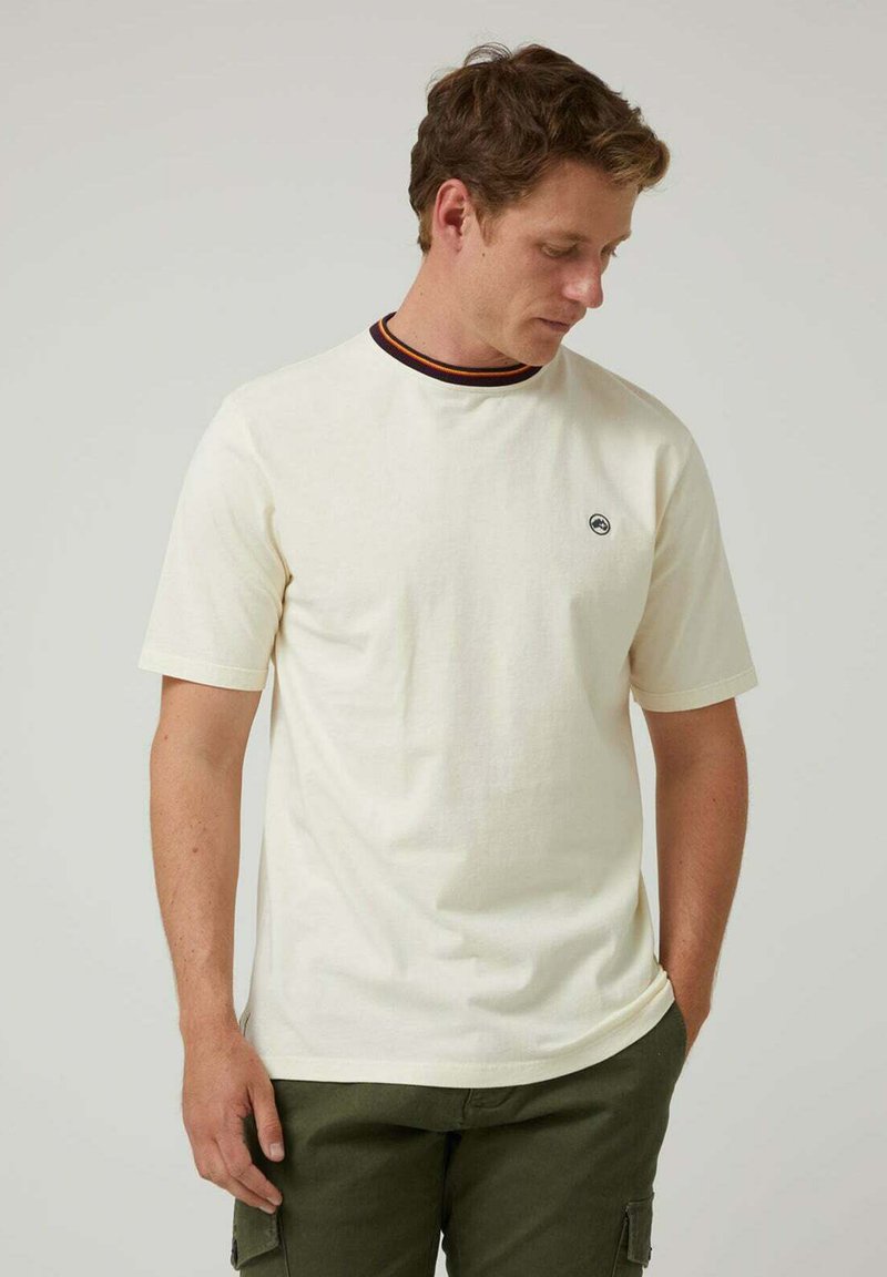 Camiseta blanca de manga corta con cuello redondo, presente un ribete a rayas en negro y naranja; pequeño logo en el lado izquierdo del pecho; material de algodón.