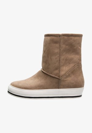 Botte en daim brun clair mi-mollet avec une semelle plateforme blanche et une bande noire le long du bord inférieur, vue de profil.