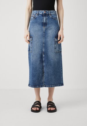Denim midi-skjørt i mellomblått med to store sidelommer, en frontslisse og rett snitt. Kombinert med svarte sandaler med stropper.