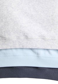 Tres jerséis de punto doblados apilados, mostrando puños acanalados en colores gris claro, azul pálido y gris oscuro.