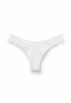 Vit stringtrosa med spetsdetaljer och en slät bomullskropp. Spetsen har ett blommönster och vågiga kanter längs midjebandet.