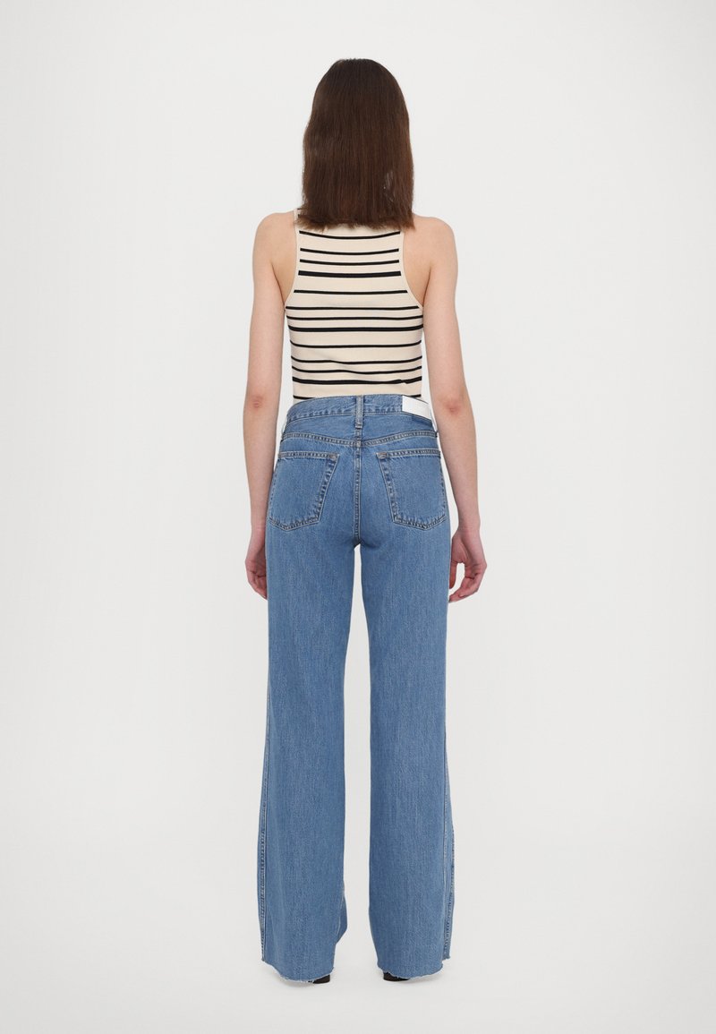 Hoch-taillierte blaue Jeans aus Denim mit weitem Bein, fünf Taschen und einem weißen Etikett am hinteren Bund. Texturierter Stoff mit Steppdetails.