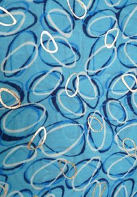 Textiel met een blauwe achtergrond, versierd met abstracte ovale vormen in tinten blauw, omrand met metallic goud. Gladde textuur.