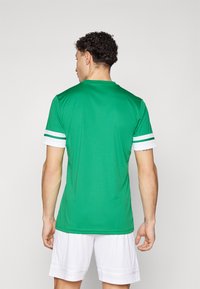 Green athletic jersey with short sleeves, featuring white stripes at the sleeve cuffs. Smooth texture, standard fit, breathable material.
