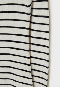Tissu en tricot blanc côtelé avec des rayures noires horizontales, montrant la couture latérale et une partie d'une manche longue.