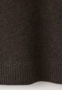 Tissu en laine brun foncé avec un ourlet côtelé en tricot en bas, montrant un matériau doux et texturé.