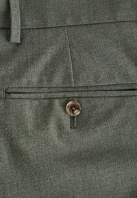 Green fabric with a smooth texture, featuring a button closure and a horizontal pocket seam for design detail.