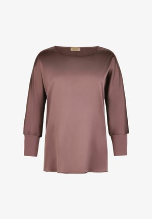 Blouse en satin mauve doux à manches longues avec larges poignets côtelés et col rond, présentée sur un fond blanc uni.