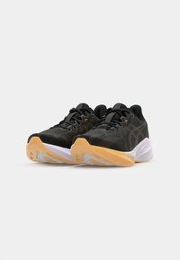 Chaussures de sport noires avec tige en maille, accents orange contrastants, semelle intermédiaire blanche et semelle extérieure en caoutchouc avec un motif texturé.