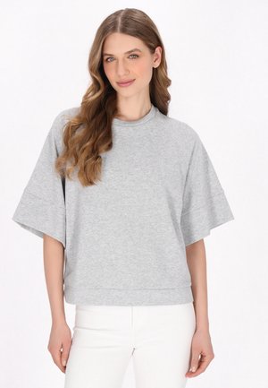 Sweatshirt gris, à manches courtes, de coupe ample, fabriqué en tissu doux, avec un col rond et une coupe décontractée. Texture lisse, détails minimaux.
