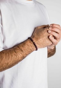 Purple bead bracelet with gold accents, worn on a wrist. Bracelet features a mix of shiny and matte textures, complementing a plain white t-shirt.