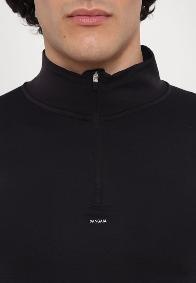 Schwarzer Reißverschluss-Pullover aus glattem, dehnbarem Material. Mit einem hohen Kragen, kurzem Reißverschluss und einem kleinen weißen Logo auf der Brust.