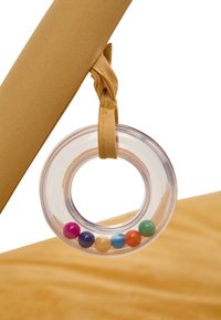 Clear circular teething ring with colorful beads, attached to a soft, golden fabric surface with a knotted, matching ribbon.