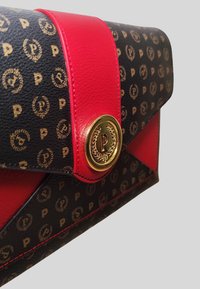 Clutch in pelle nera con accento rosso, dotato di una chiusura con logo dorato e un motivo di piccoli cerchi dorati con un design a 'P'.