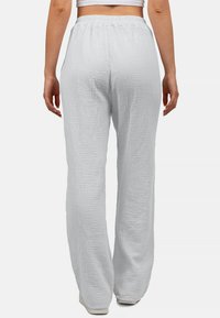 Witte, lichte, textuurijke broek met brede pijpen en een elastische taille, met een gekreukt patroon en een relaxte pasvorm. Geschikt voor casual draag.