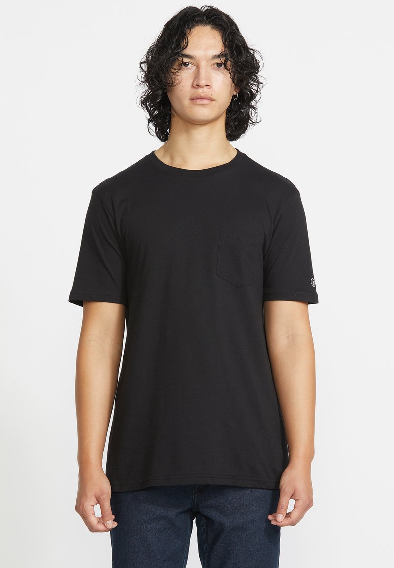 Sort kortærmet t-shirt med rund halsudskæring, har en lomme på venstre bryst og en diskret logo detalje på ærmet. Fremstillet af blødt stof.