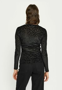 Must must sleeves must-suurusega musta tippu, mis on valmistatud läbipaistvast ja venivast materjalist, millel on mati leopardi mustri muster. Sile tekstuur ja keha lähedane siluett.