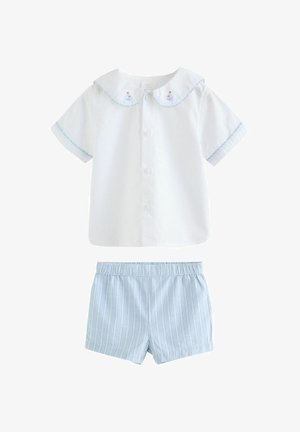 Bijela košulja kratkih rukava s kopčanjem na gumbe i vezom jedrilica na ovratniku, uparena s kratkim hlačama s elastičnim pojasom u svijetloplavim i bijelim prugama.