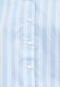 Ανοιχτό μπλε ύφασμα με κάθετες λευκές και σκούρες μπλε ρίγες, με μια κεντρική σειρά από λευκά κουμπιά.