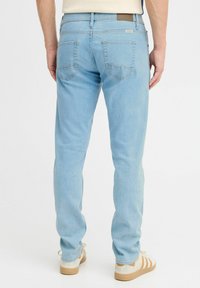 Jeans in denim azzurro chiaro con vestibilità slim, dotati di tasche posteriori con cuciture curve e una patch in pelle sulla cintura.