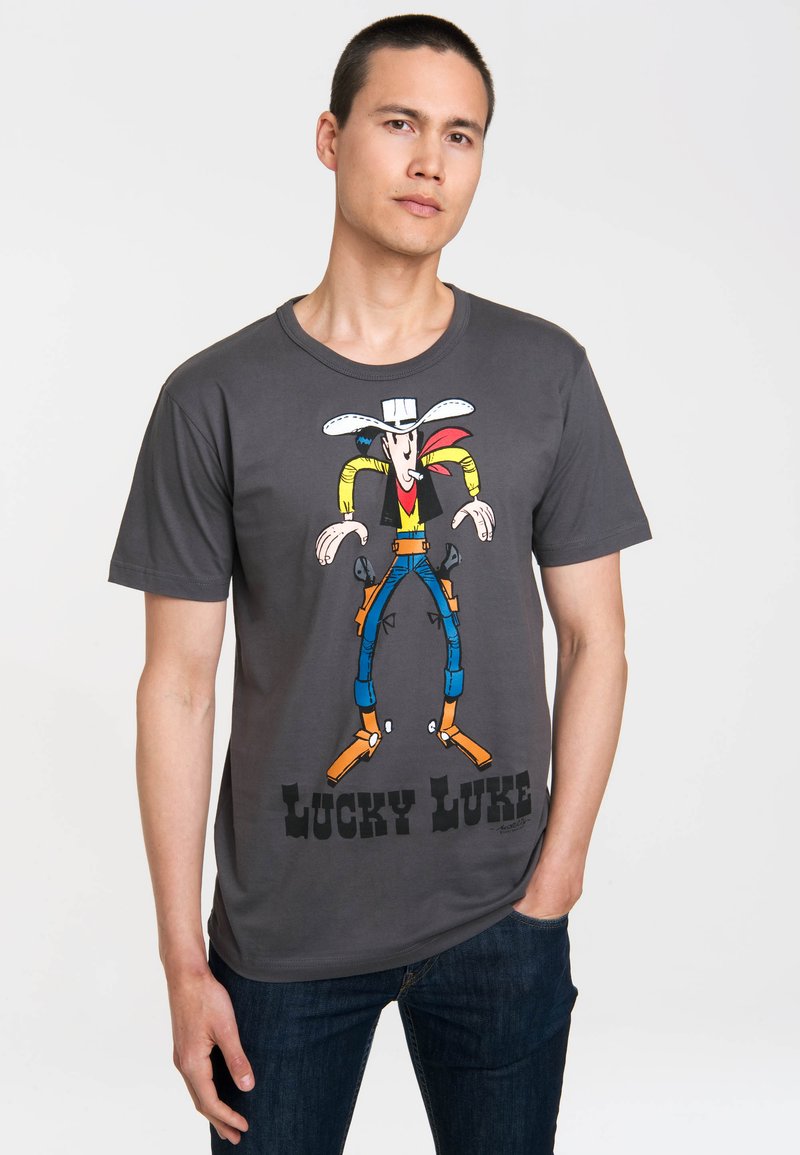 Graues Baumwoll-T-Shirt mit einem bunten Cartoon-Graphic von Lucky Luke, der einen weißen Hut, ein rotes Halstuch trägt und darunter Text.