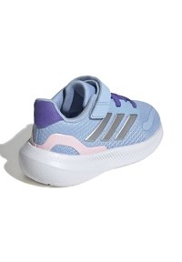 Chaussure de sport bleu clair avec des accents violets et roses, dessus en mesh et semelle en caoutchouc blanc ; elle dispose d'une sangle Velcro et de détails argentés.