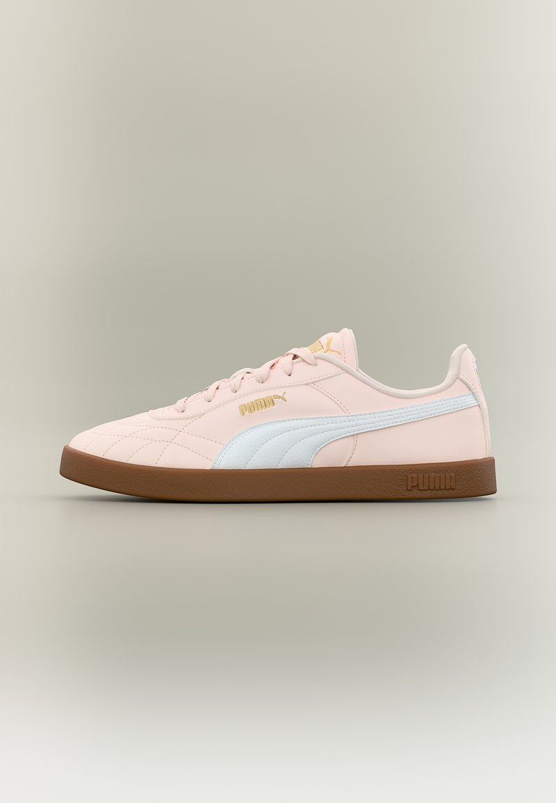 Ανοιχτό ροζ αθλητικό παπούτσι Puma με λευκή ρίγα, χρυσό λογότυπο και καφέ σόλα, απεικονίζεται σε προφίλ σε ουδέτερο φόντο.