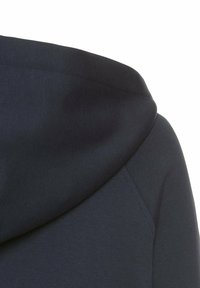 Dunkelblauer Kapuzenpullover aus weichem, strukturiertem Stoff. Verfügt über eine abgerundete Kapuze und sichtbare Nähte entlang des Halsausschnitts und der Schultern.