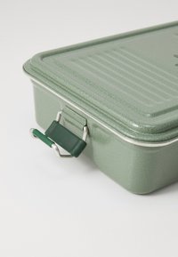 Green enamel-coated metal container with a textured surface, rectangular shape, and a metallic latch with a green rubber grip.