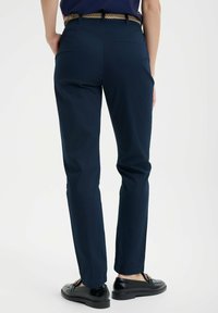 Granatowe chinosy wykonane z mieszanki bawełny, o slim fit, prostych nogawkach i wplecionym pasku. Gładka tekstura z minimalnymi zdobieniami.