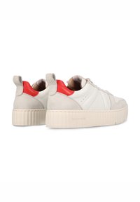 Weiße Ledersneaker mit hellgrauen Wildlederakzenten und einer roten Ferse. Sie verfügen über eine dicke, strukturierte Sohle und Schlaufen an der Rückseite.