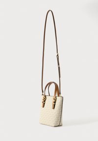 Beige lærredshåndtaske med et monogrammønster, brune læderhåndtag og en aftagelig skulderrem, der har guldfarvede hardware-detaljer.
