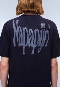 Navyblaue Baumwoll-T-Shirt mit einem großen, verwitterten grauen "Napapijri"-Logo auf der Rückseite, kurzen Ärmeln und Rundhalsausschnitt.