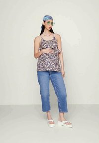 Top leve com padrão floral, alças ajustáveis e franzido na cintura. Combinado com jeans azul claro de corte relaxado e sandálias de plataforma brancas.