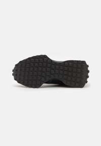 Suela de zapato deportivo negro con patrón de tracción circular, hecha de goma. Presenta una superficie texturizada para mejorar el agarre.
