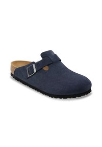 Sabot en daim bleu marine avec une forme arrondie, boucle réglable en argent, semelle en liège et semelle en caoutchouc noir avec un profil antidérapant.