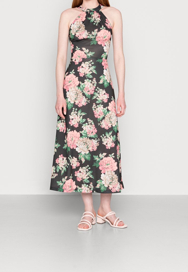 Robe halter en gris foncé avec des motifs de fleurs roses et vertes. La robe est à mi-genoux, en tissu doux avec un corsage ajusté.