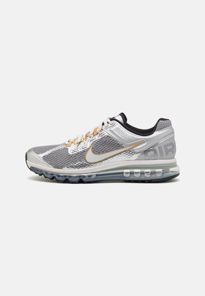 Baskets Nike Air Max grises et blanches avec semelle à coussin d'air visible, accents dorés, empeigne en mesh et texte "AIR" sur le talon.