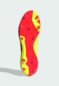 Suola delle scarpe da calcio con colori vivaci rosso e giallo. Presenta sei tacchetti angolari e una superficie testurizzata, con "PREDATOR" stampato sul lato.