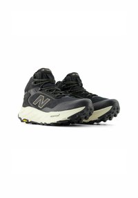 Scarpe da trekking nere con una parte superiore texturizzata, una suola bianca imbottita e un battistrada in gomma per la trazione. Presentano un grande logo "N" sul lato.