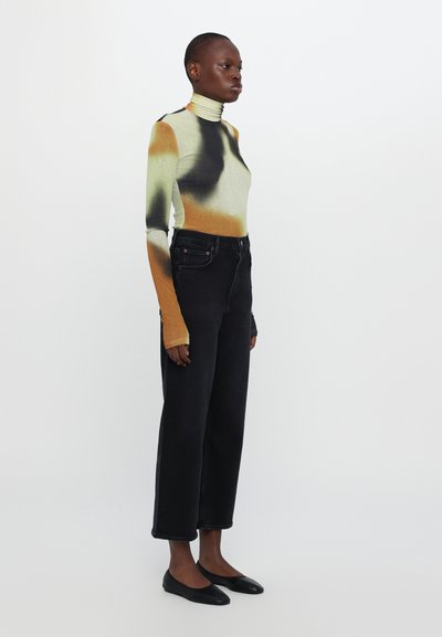 Long-sleeve turtleneck in gradient shades of green, orange, and black; paired with high-waisted black straight-leg jeans and black flats.