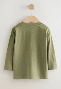 T-shirt a maniche lunghe, verde oliva, con collo rotondo, realizzata in tessuto morbido. Presenta un design semplice con una texture liscia e dettagli di cucitura minimi.