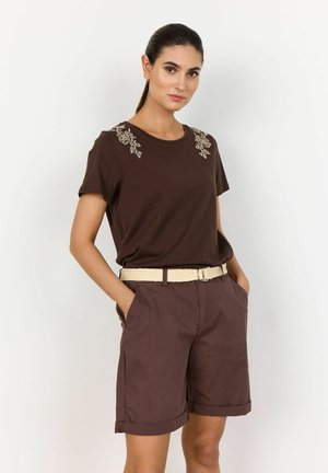 Bruine katoenen t-shirt met bloemenborduursel op de schouders, gecombineerd met bruine shorts met omgeslagen zomen en een gevlochten beige riem.