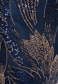 Tissu bleu foncé avec une broderie florale complexe en sequins dorés et bleu marine formant des motifs de pétales détaillés.